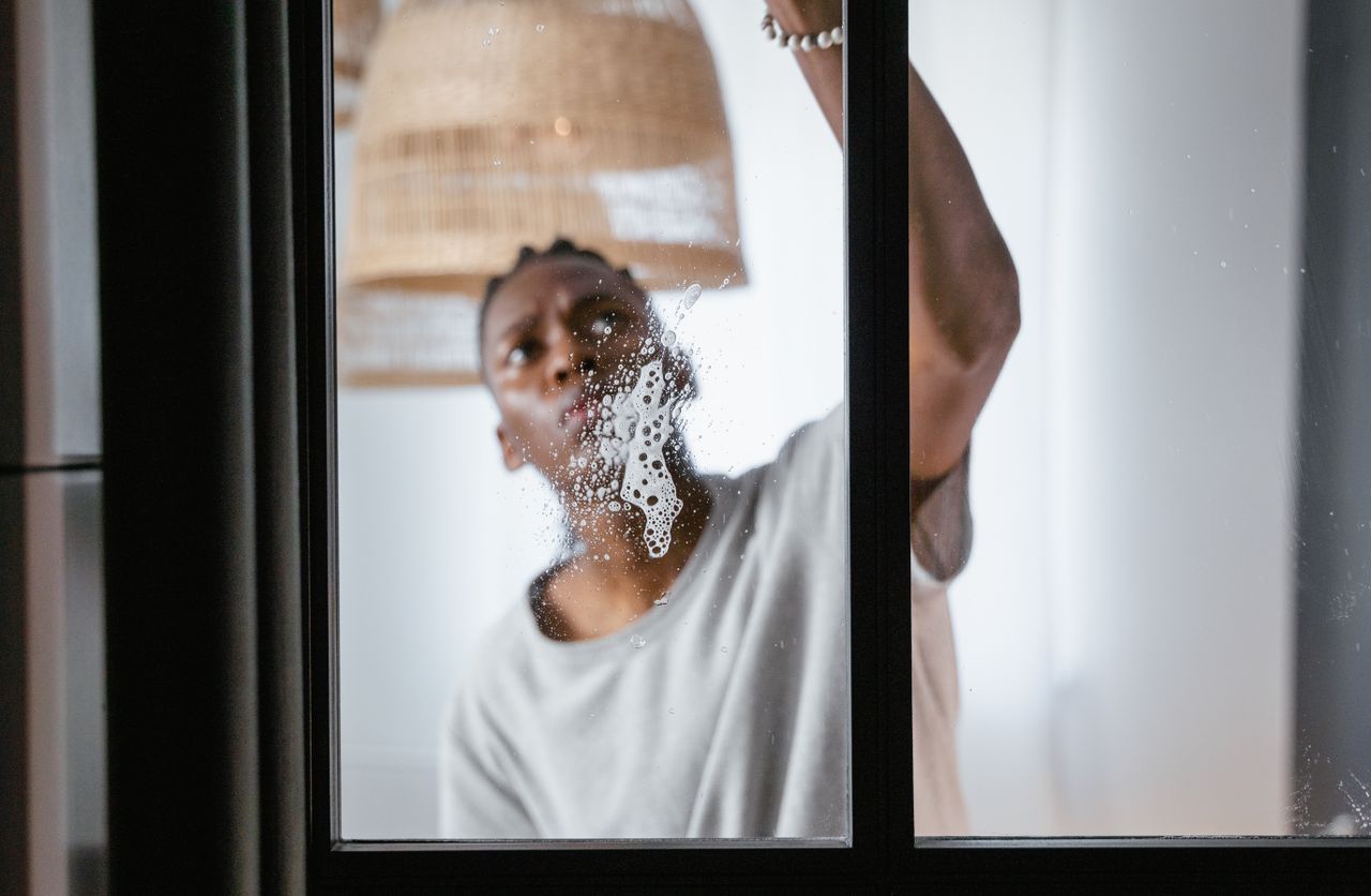 portfolio-04 An adult male cleaning a glass window indoors, focusing on household chores and cleanliness.